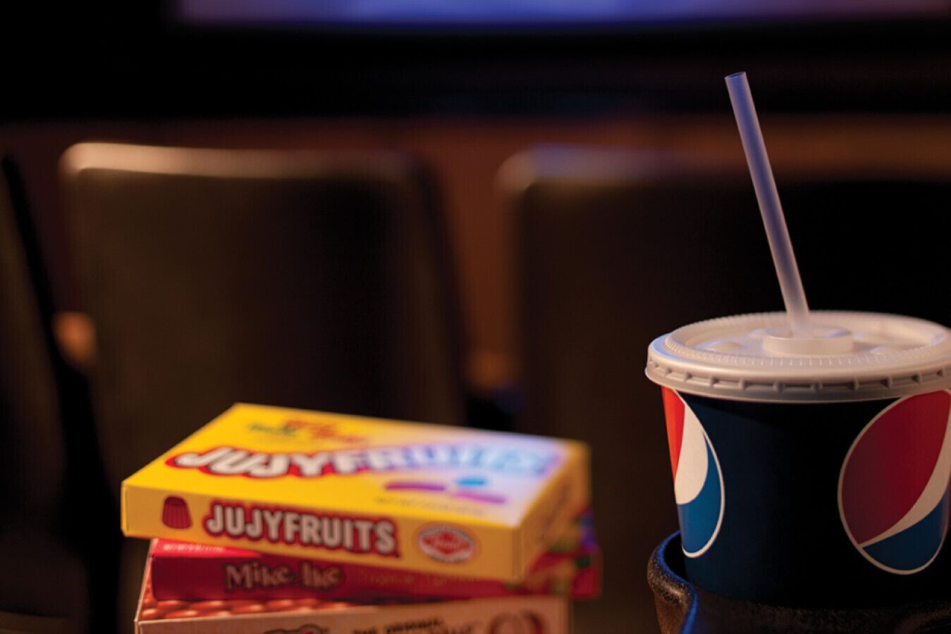 A box of Jujyfruits and a Pepsi cup on a table.