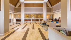 Eine geräumige Lobby mit einer Rezeption, einer Sitzecke und einer dekorativen Wand.