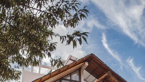 Une maison à deux étages avec un balcon, une terrasse couverte et un jardin.