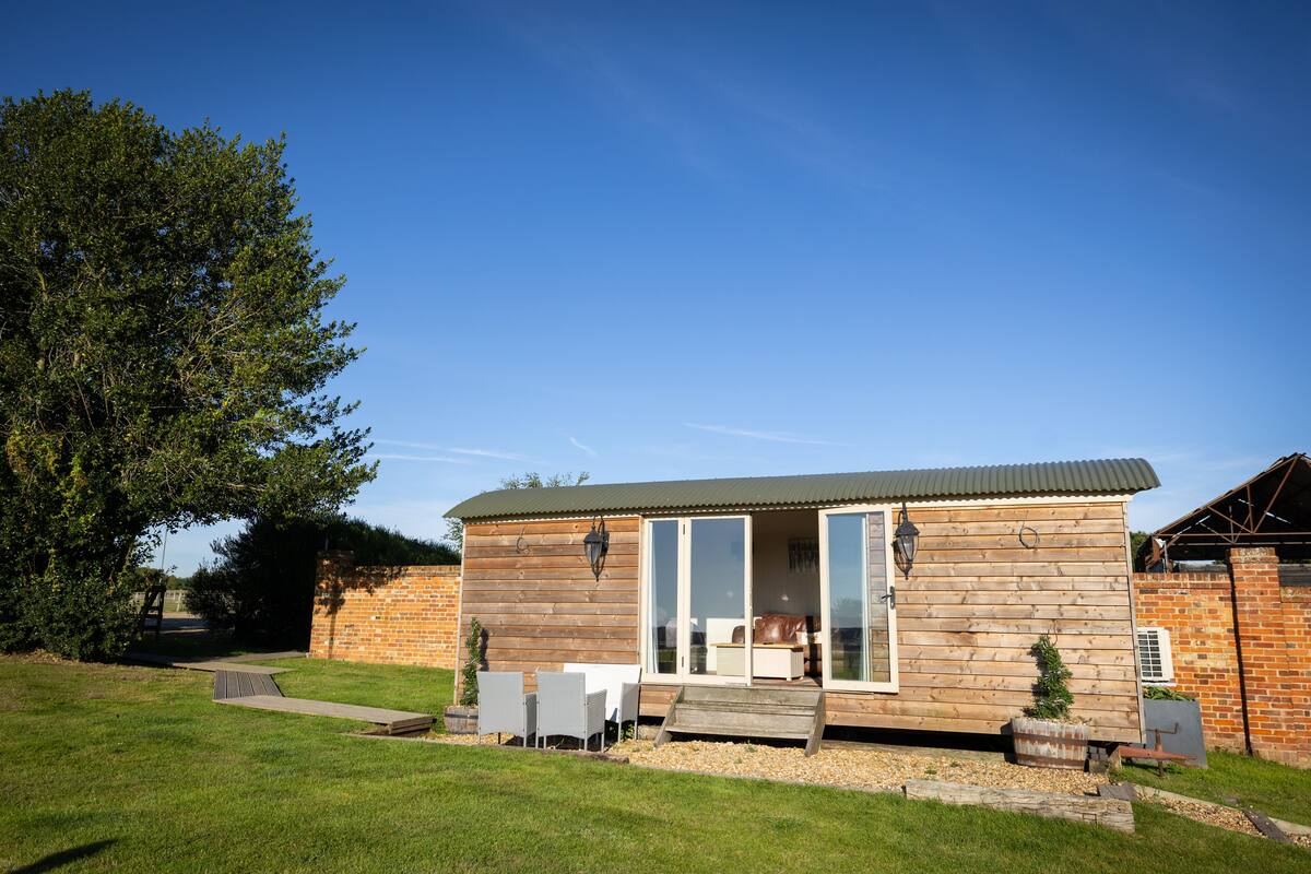 A wooden cabin with a patio, a sliding glass door, and a brick wall.