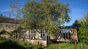 A rustic wooden cabin with a porch, surrounded by lush greenery and a clear blue sky. - Coltsfoot Country Retreat (Knebworth)