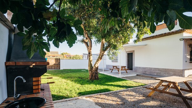 An outdoor patio area with a grill, a sink, and a picnic table. - .................... (AN)