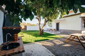 An outdoor patio area with a grill, a sink, and a picnic table. - .................... (AN)
