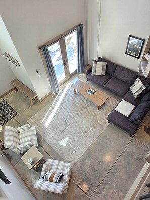 A modern living room with a sofa, a bench, a coffee table, and a patterned rug.