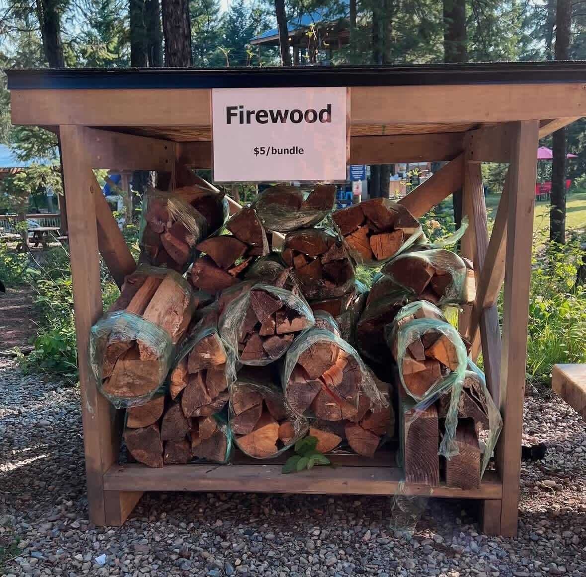 Een stapel houtblokken met het label 'Firewood $5/bundle' in een houten constructie.