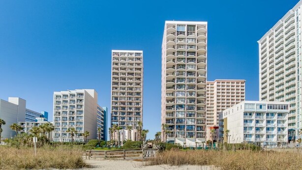A beachfront hotel with multiple high-rise buildings, featuring balconies and a sandy beach in the foreground. - Palms Resort Getaway (Myrtle Beach)
