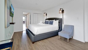 A modern bedroom with a large bed, a chair, and a bedside table. - Palms Resort Getaway (Myrtle Beach)