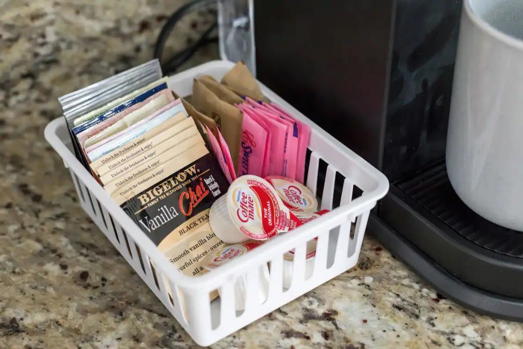 A basket containing tea bags and coffee pods on a kitchen counter.