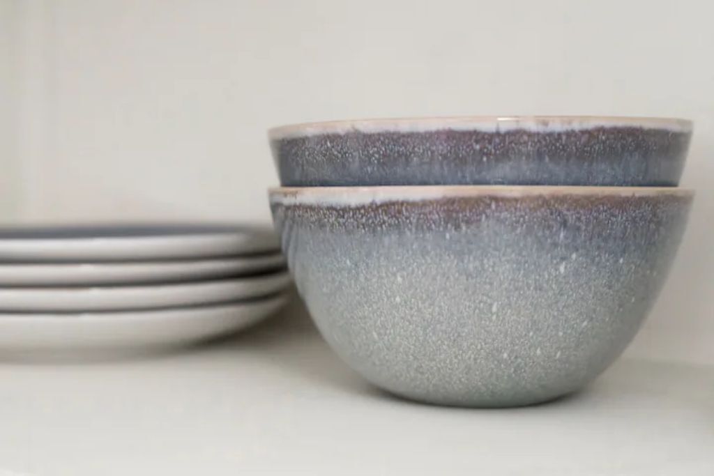 A stack of grey ceramic bowls and plates.