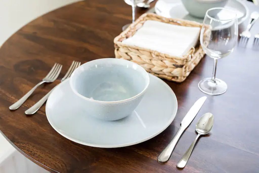 A dining table with a bowl, cutlery, and a glass of water.