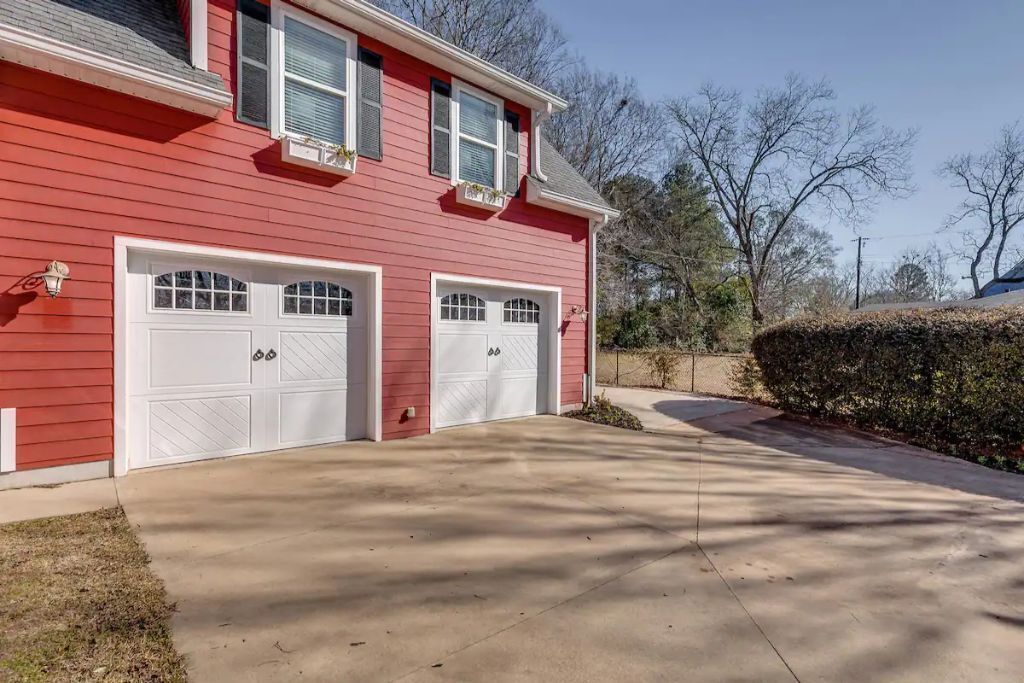 A two-story house with a red exterior and two white garage doors.