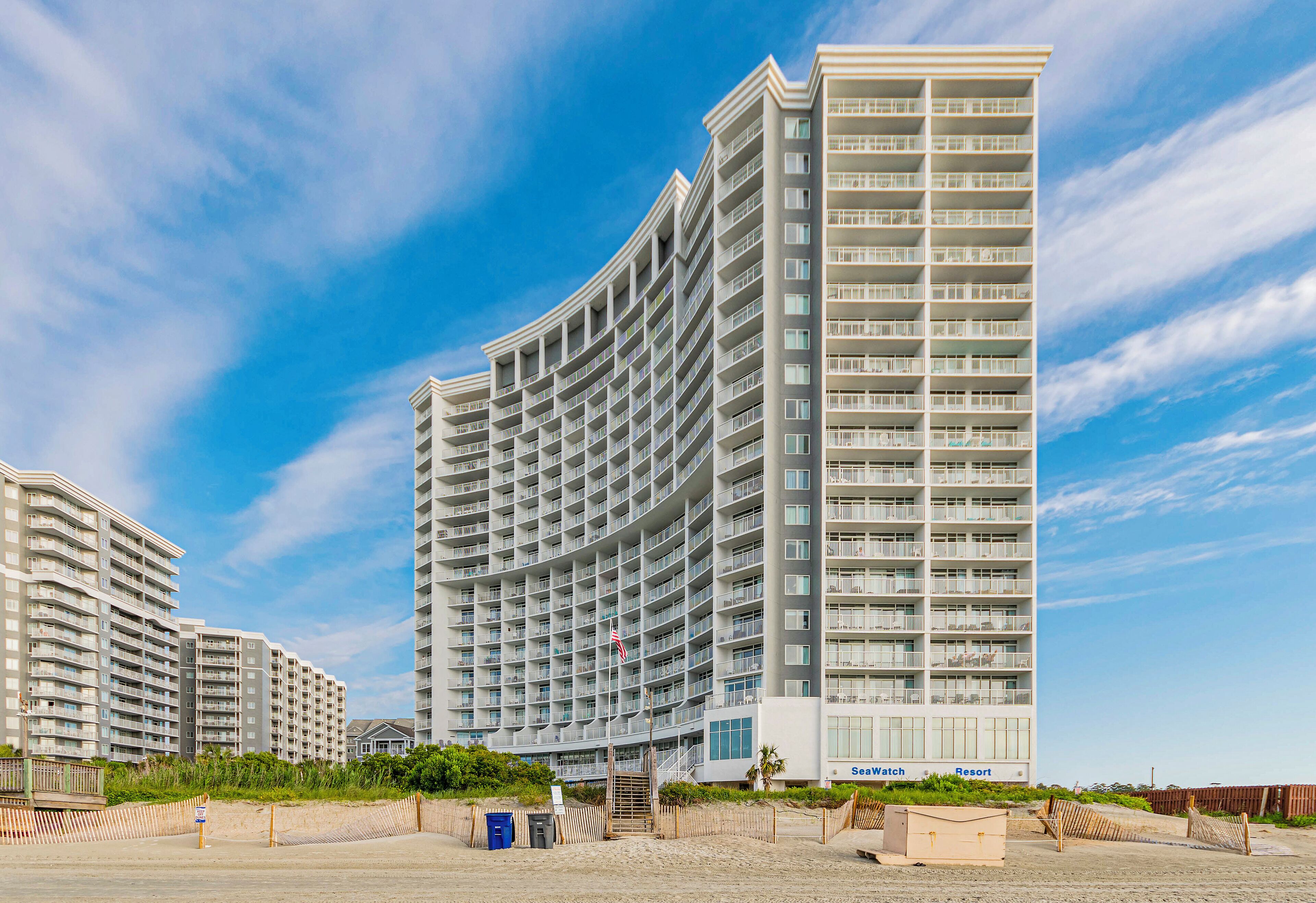 Un hôtel à plusieurs étages, doté d’une façade incurvée, de balcons et offrant une vue sur la plage.