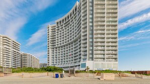Un hotel de varios pisos con fachada curva, balcones y vista a la playa.