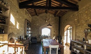 A rustic dining area with a wooden table and chairs, surrounded by stone walls and wooden beams.
