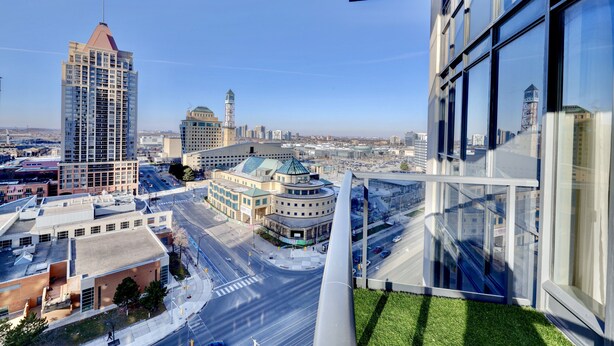 Un immeuble de grande hauteur doté d’une façade moderne en verre, une tour imposante et un bâtiment circulaire surmonté d’un dôme verdoyant.