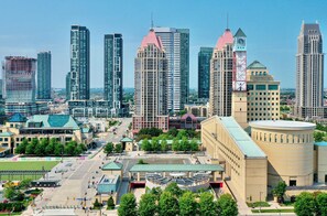 A cityscape with modern high-rise buildings, a large public square, and a prominent circular building with a green roof.