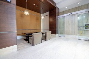 A modern conference room with a glass partition, a wooden accent wall, and a hanging light fixture.