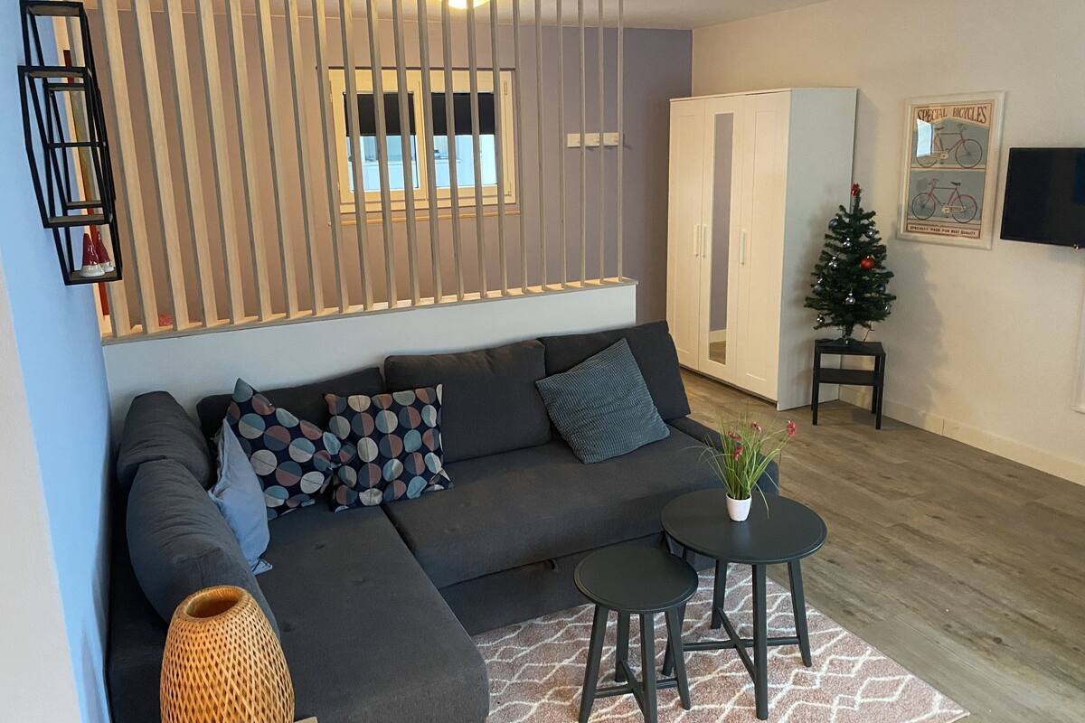 A modern living room with a sectional sofa, a small round table, and a decorative plant.
