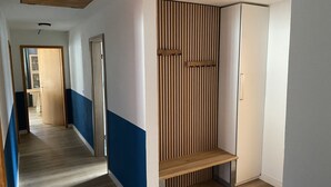 Un passadís amb una banca de fusta, una porta i una paret amb lamel·les verticals.