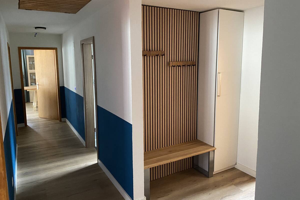 A hallway with a wooden bench, a door, and a wall with vertical slats.