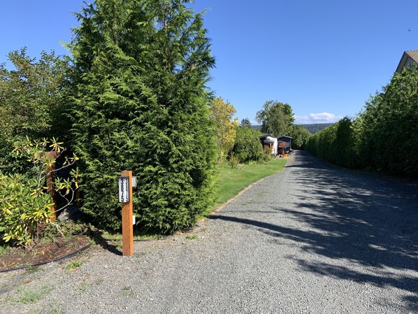 A gravel driveway leading to a property with a wooden signpost and a mailbox.