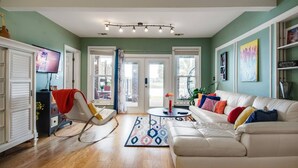 Un salon avec un canapé blanc, un fauteuil à bascule, un téléviseur et une table basse.