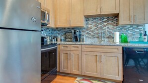A kitchen with wooden cabinets, a stainless steel refrigerator, a microwave, a coffee maker, and a tiled backsplash. - Waterfront Fishing Dock FirePit HotTub Deck GrillB (Hanahan)
