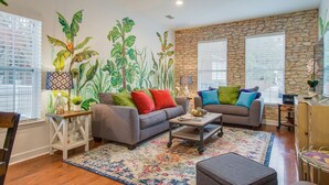 A living room with two sofas, a coffee table, a patterned rug, and a stone wall. - Waterfront Fishing Dock FirePit HotTub Deck GrillB (Hanahan)