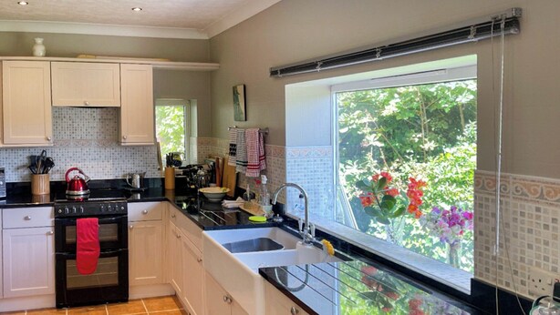 A kitchen with white cabinets, a black countertop, and a window with a view of greenery.