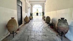 A corridor with stone flooring, large ceramic pots, and a view of a building in the distance. - LOFT in downtown with TERRACE, Wifi,Air Cond.Free parking 2/3p (Palermo)