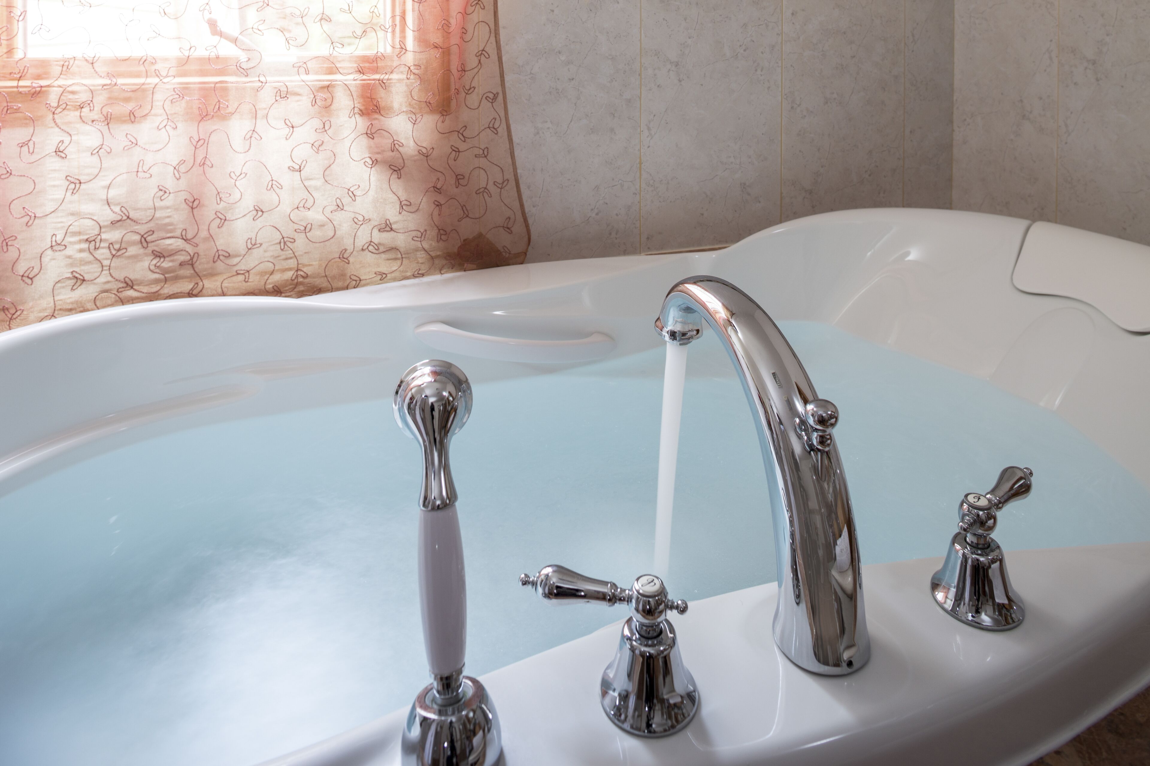 Una bañera con un solo grifo y un cabezal de ducha.