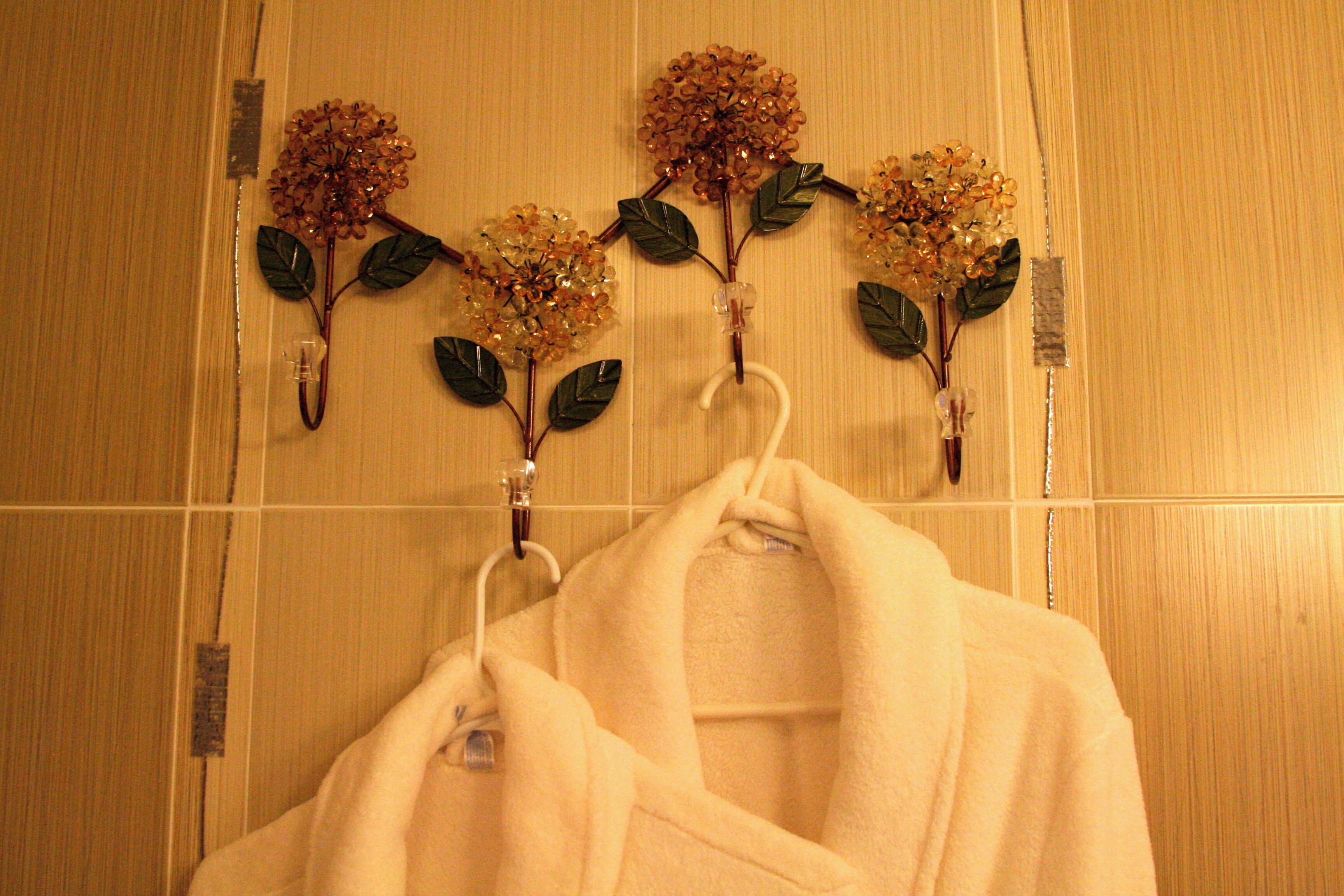 A bathroom with wooden walls, a towel rack with two towels, and decorative flowers on the wall.