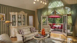 Un salón amplio con un sofá color beige, una mesa de centro de vidrio y un paraguas rojo en el exterior.