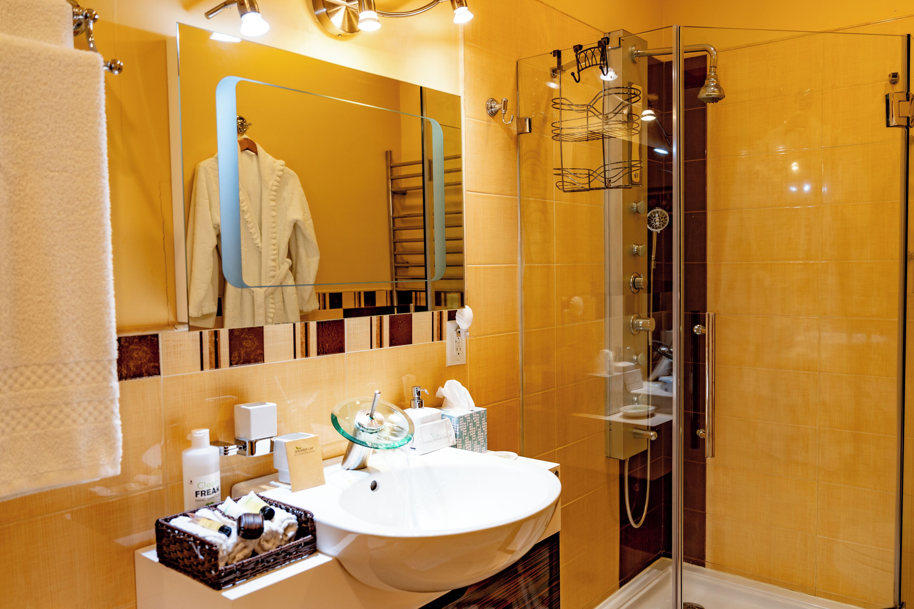 Un baño moderno con ducha de vidrio, un lavamanos blanco y un espejo sobre él.