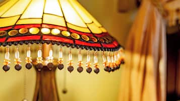 A close-up of a stained glass lamp with a wooden base and hanging beads.