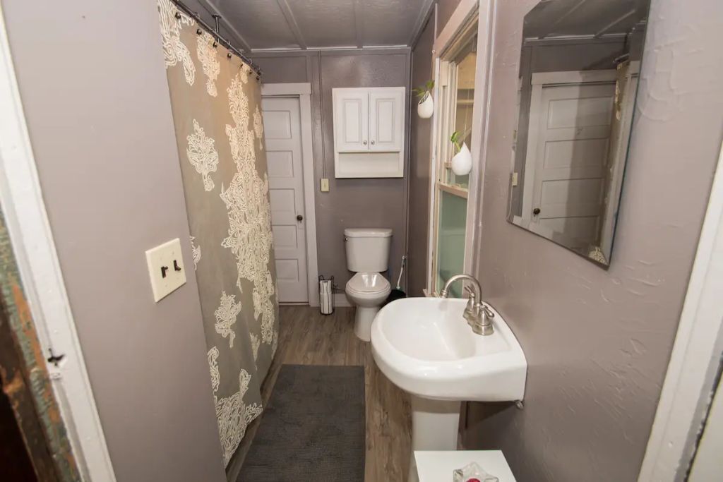 Ein schmales Badezimmer mit Toilette, Waschbecken und einem Schrank darüber.
