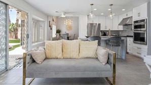 A modern kitchen with stainless steel appliances, a grey sofa with patterned cushions, and a chandelier. - ❤ BRAND NEW POOL, Clean 4BR/3BA Modern Chic Home ❤ (Henderson)