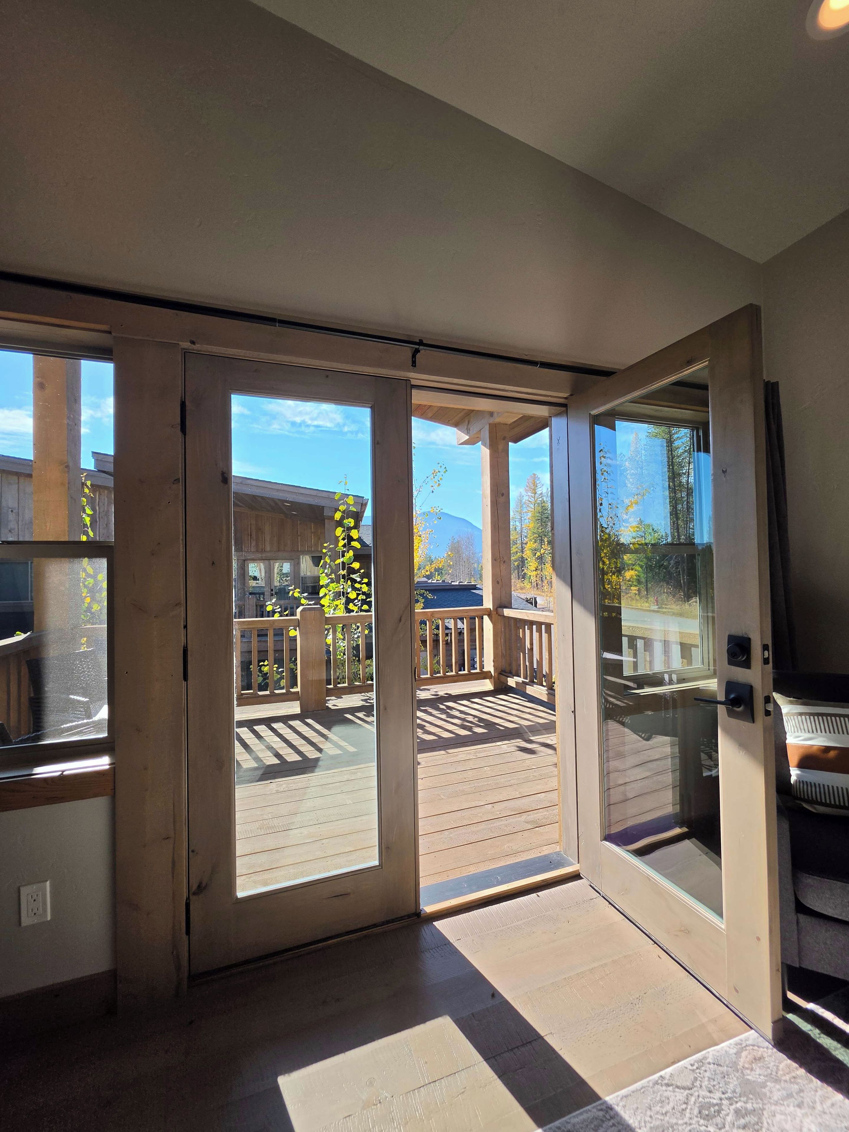 A room with a large sliding glass door leading to an outdoor deck with a wooden railing.