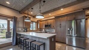 Una cocina moderna con una isla grande, electrodomésticos de acero inoxidable y armarios de madera.