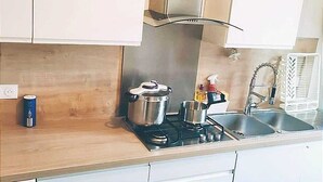 Eine Küche mit Herd, Töpfen, Spüle und Fenster.