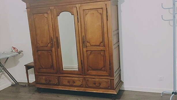 Ein Holzschrank mit Spiegel, ein kleiner Beistelltisch und ein Kleiderständer.