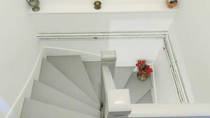 Eine weiße Treppe mit Handlauf, die zu einer Zwischenebene mit einem kleinen Strauß roter Blumen führt.