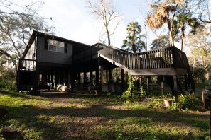 Ein rustikales Holzhaus mit einer Veranda und einer Treppe, die zu einer oberen Ebene führt.