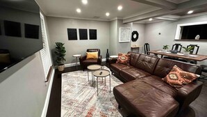 Een moderne woonkamer met een bruine leren bank, twee ronde bijzettafeltjes en een kamerkleed met een patroon.