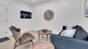 A modern living room with a blue sofa, a wooden coffee table, and a unique woven wall art piece. - Sunny, bright & natural apt, centrally located (Montréal)