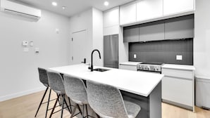 A modern kitchen with a central island, grey chairs, and stainless steel appliances. - Spacious & peaceful 2 bedrooms, sleep 6 (Montréal)