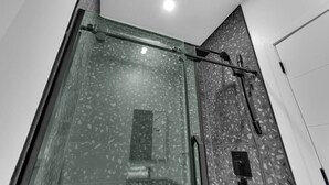 A modern shower area with a glass enclosure and a rain shower head. - Spacious & peaceful 2 bedrooms, sleep 6 (Montréal)