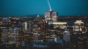 A cityscape at night with illuminated buildings and a prominent tower with a light beam.