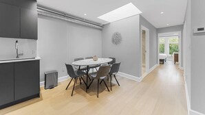 A modern kitchen with grey cabinets, a round dining table with chairs, and a skylight above. - Stunning 2 beds, 2 baths, AAA location, rooftop (Montréal)