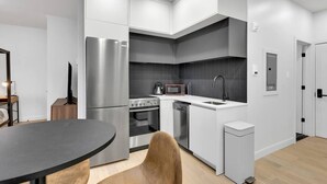 A modern kitchen with white cabinets, a stainless steel refrigerator, a microwave, and a sink. - Lovely, spacious & stylish studio, sleeps 3 (Montr éal)